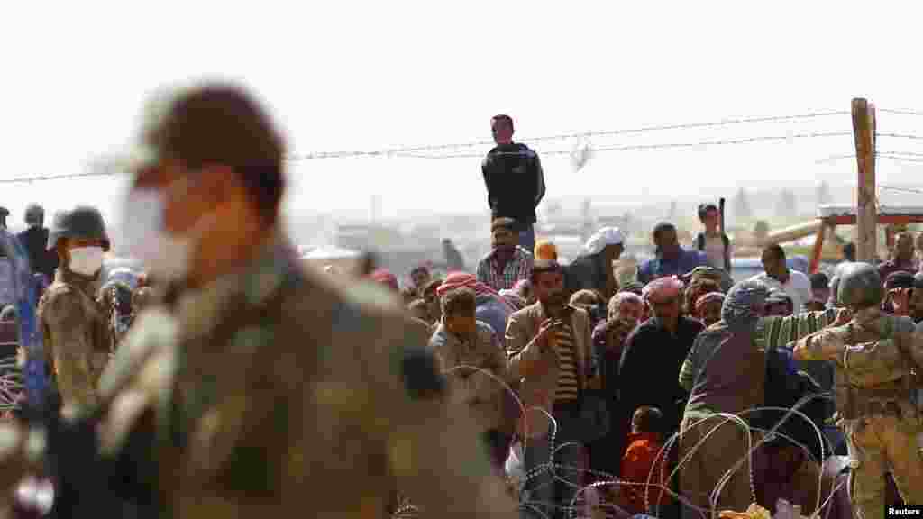 A Kobani, des réfugiés kurdes attendent de traverser la frontière syrinne près de la ville turque de Suruc dans la province de Sanliurfa. (Le 2 octobre 2014).