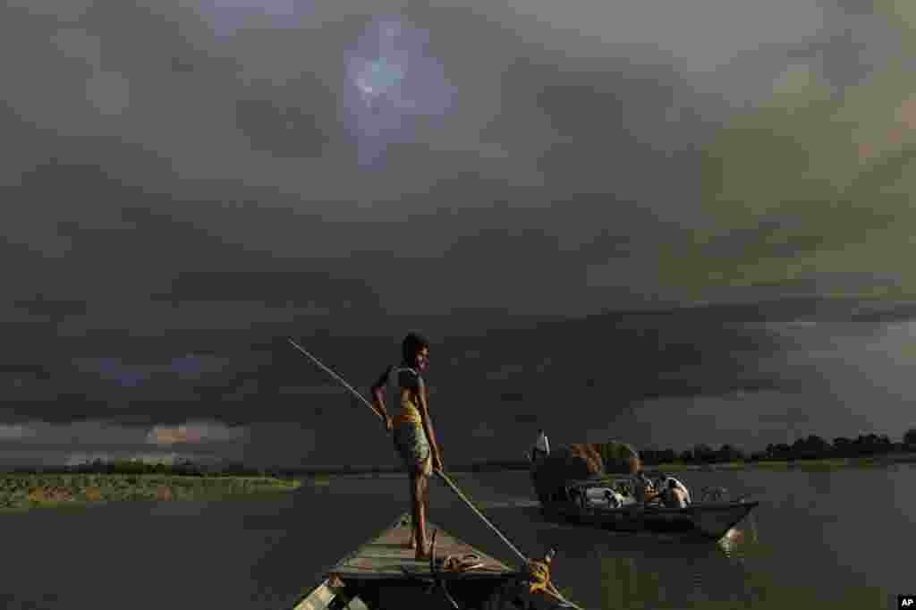 A boat carries flood relief materials as monsoon clouds surrounded the flood affected Gagalmari village in Assam state, India, July 2, 2012.