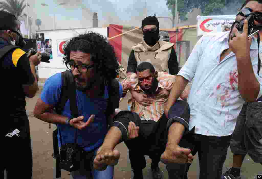 Supporters of ousted Islamist President Mohammed Morsi carry another as Egyptian security forces clear a sit-in camp set up near Cairo University in Cairo's Giza district, Egypt, August 14, 2013. 