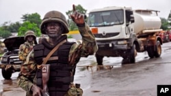 A Liberian soldier stops people at a security checkpoint set up to clamp down on people trying to travel to the capital from rural areas hard-hit by the Ebola virus, on the outskirts of Monrovia, Aug. 7, 2014.