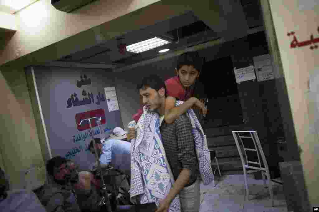A Syrian volunteer carries a child wounded by Syrian Army shelling at Dar al-Shifa hospital in Aleppo, Syria, October 11, 2012.