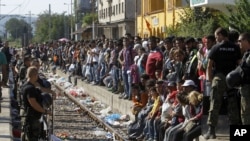 Polisi menjaga jalur kereta sebelum sebuah kereta yang membawa migran ke Serbia memasuki stasiun kereta di kota selatan Makedonia, Gevgelija, 23 Agustus 2015. 