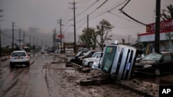 Typhoon-damaged cars sit on the street covered with mud, Oct. 14, 2019, in Hoyasu, Japan. Rescue crews dug through mudslides and searched near swollen rivers as they looked for those missing from typhoon Hagibis