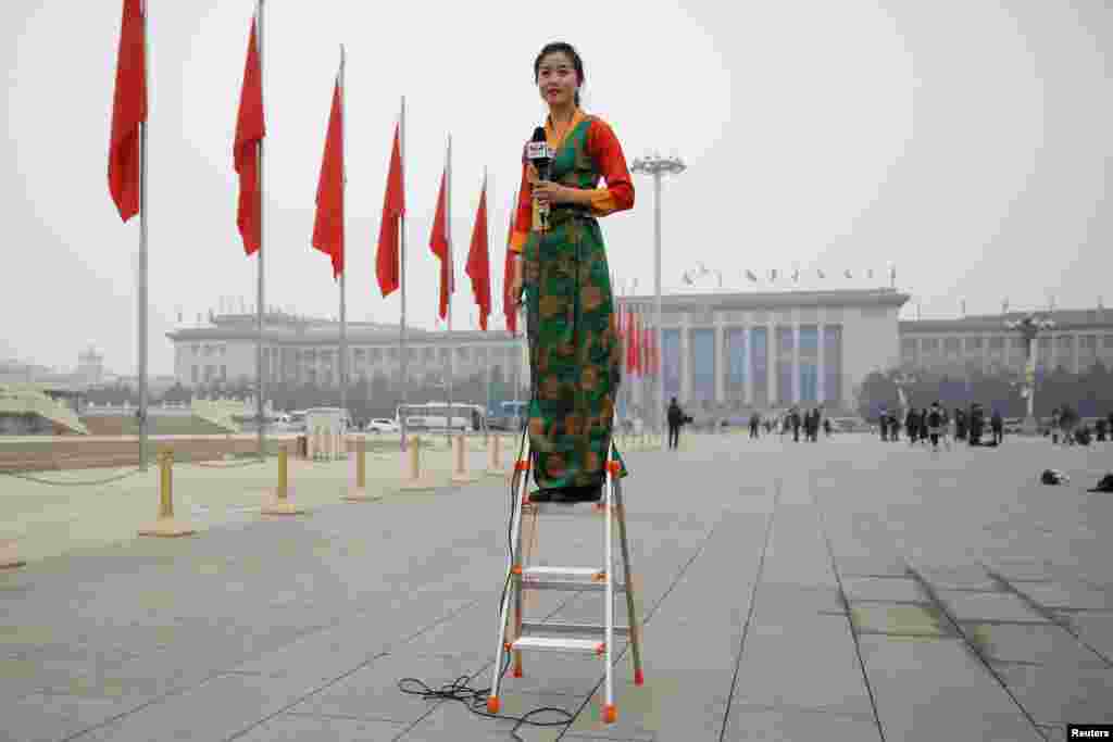 2018年3月3日,中国人民政治协商会议在北京开幕之前,在人民大会堂外的空荡荡的天安门广场,一位记者站在梯子上做报道。当天北京雾霾严重,PM2.5指数超过200,非常不利于健康。看来今年当局并没有刻意营造“两会蓝”。