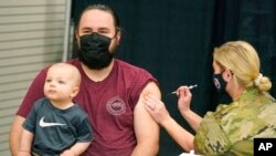 Isaac Hoffman holds his son Leo, 10 months, while receiving his Pfizer vaccine, March 25, 2021, in Spanish Fork, Utah. 