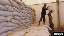 Dua pria mengangkat karung berisi bantuan makanan di Sevare, Mali (4/2). (Reuters/Alain Amontchi)