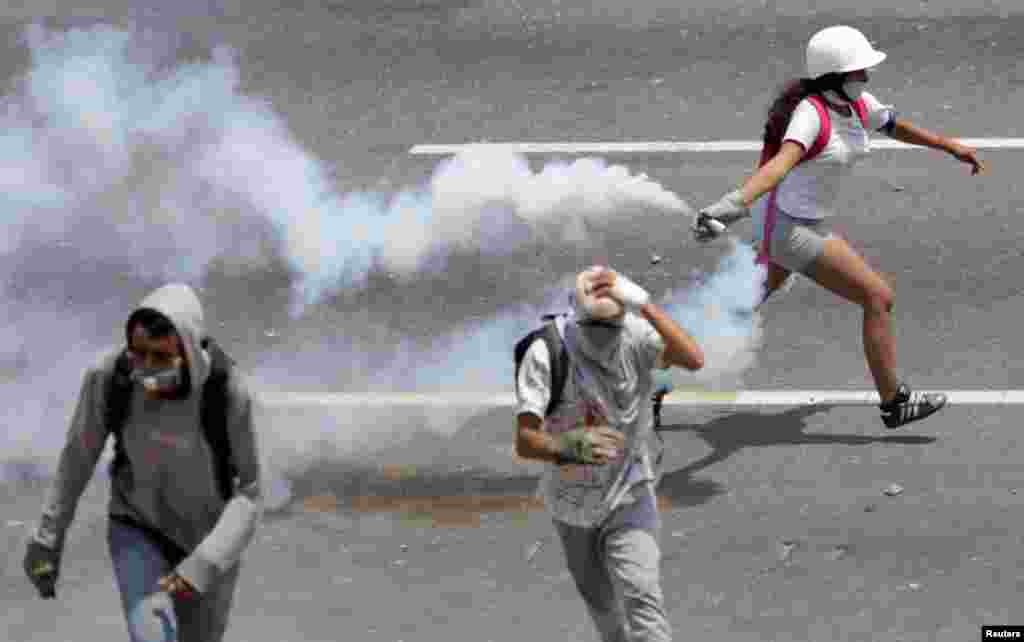 An opposition supporter runs with a tear gas canister during a rally against the government of Venezuela's President Nicolas Maduro and to commemorate May Day in Caracas, May 1, 2019.