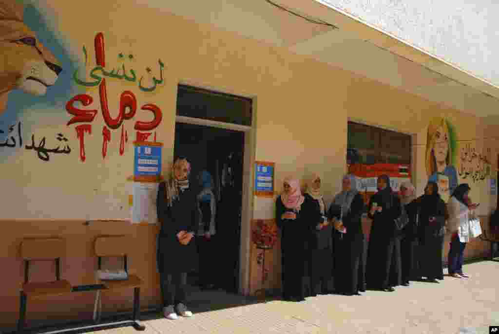 Libyan voters line up at a polling station in Benghazi, July 7, 2012. Jubilant Libyans marked a major step toward democracy after decades of rule by dictator Moammar Gadhafi. "Don't forget the blood of the martyrs" is in Arabic at left.