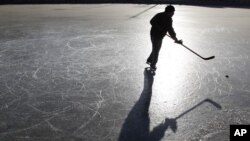 A skater plays ice hockey on a frozen lake in Beijing December 23, 2010.