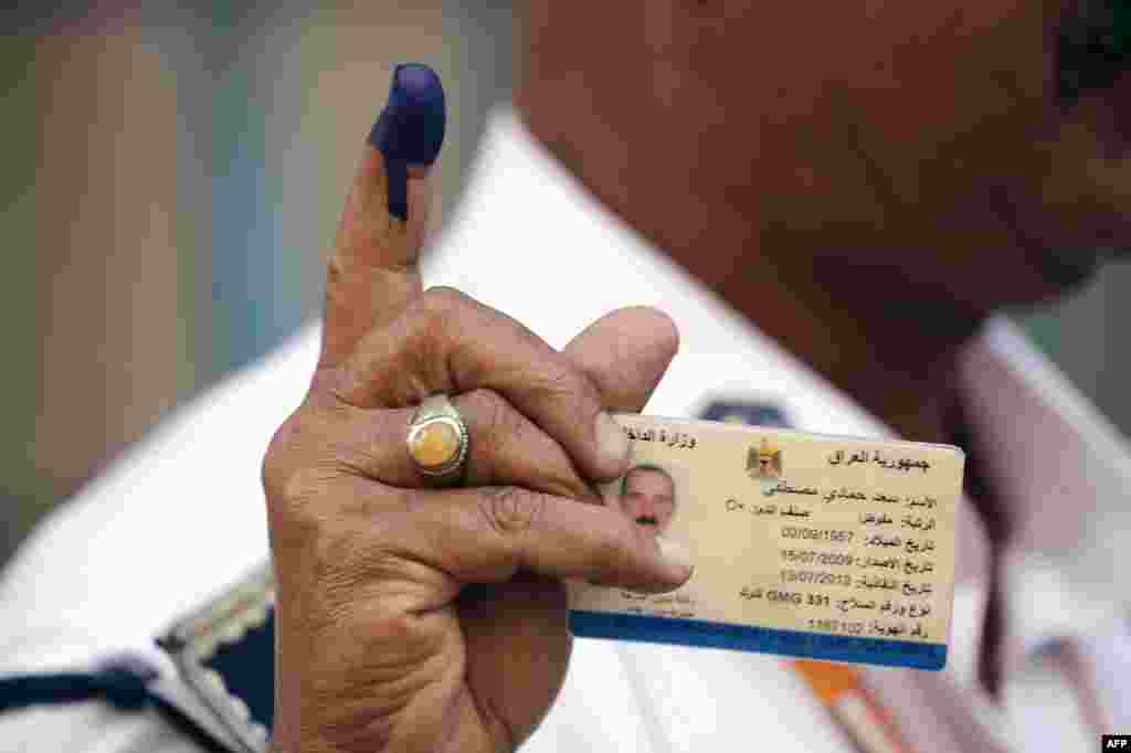 An Iraqi policeman shows his ink-stained finger and his ID after casting his ballot at a school in Baghdad's Karrada commercial district.