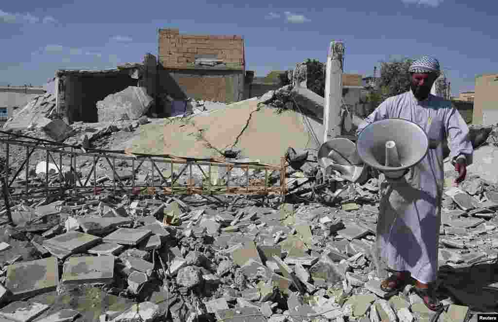 A man stands on a damaged street filled with debris in Raqqa province, eastern Syria, June 10, 2013.