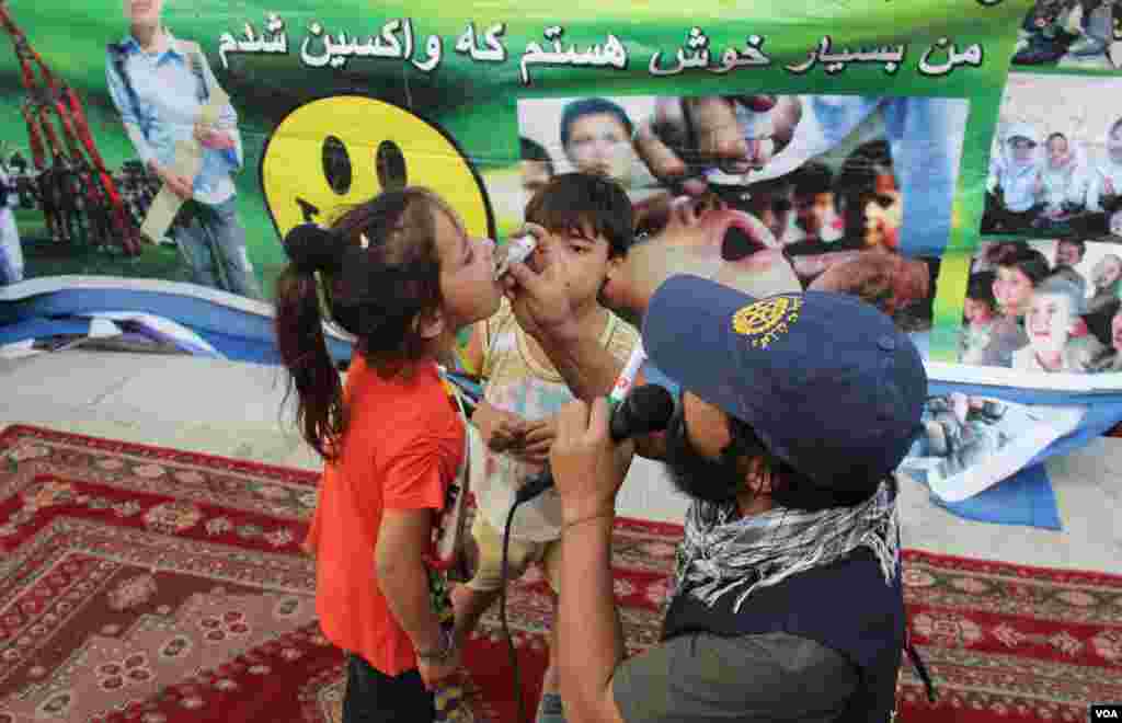 کارمند صحی در حال چکاندن قطره واکسین پولیو به دهان یکی از اطفال 