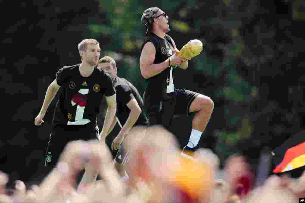 The German national soccer team members Lukas Podolski (right), Per Mertesacke (left) and Thomas Mueller, celebrate in Berlin, July 15, 2014.