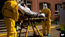 A coronavirus patient is transferred from a hospital to a home for the elderly by members of the medical staff of Klinicare in Brussels, April 1, 2020.