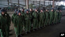 FILE - Russia-backed rebels are seen lined up in front of tanks near Novoazovsk, eastern Ukraine, Oct. 21, 2015.