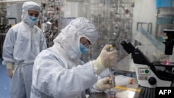 Seorang petugas riset melakukan tes vaksin eksperimental Covid-19 di laboratorium Biotek Sinovac, Beijing, 29 April 2020. (Foto: NICOLAS ASFOURI / AFP)