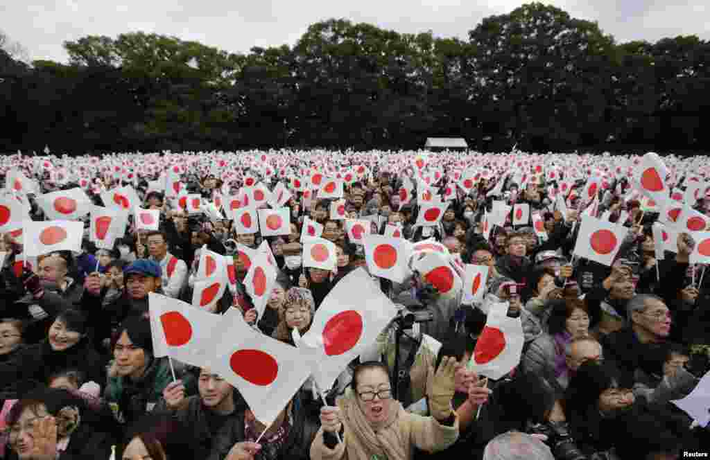 Well-wishers wave Japanese national flags to celebrate Japan's Emperor Akihito's 80th birthday at the Imperial Palace in Tokyo, Dec. 23, 2013. 