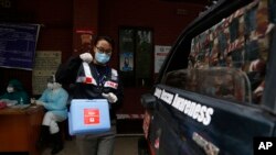 Punam Karmacharya, 22, of the RNA-16, Rescue and Awareness volunteer group, carries a box containing swab samples of patients to deliver it to a testing center, at a hospital in Bhaktapur, Nepal, May 26, 2020.