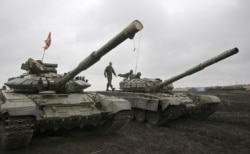 FILE - A member of the self-proclaimed Donetsk People's Republic forces walks on top of a tank during a drill outside Torez, Donetsk region, Ukraine, Sept. 14, 2015.