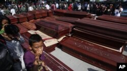 Warga melewati barisan peti jenazah yang disiapkan untuk para korban pesawat Hercules yang jatuh, di luar sebuah rumah sakit di Medan 1/7). (AP/Binsar Bakkara)