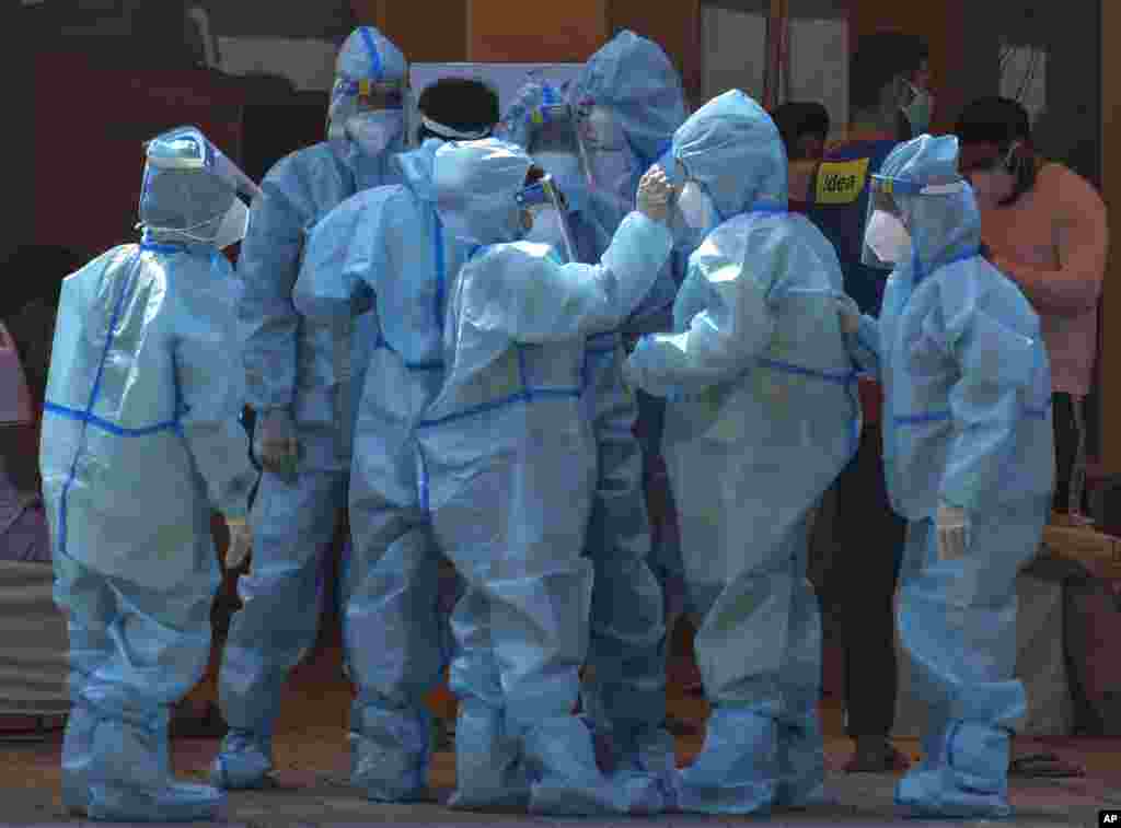 Health workers and volunteers in personal protective suits wait to receive patients outside a COVID-19 hospital at a Sikh Gurdwara in New Delhi, India.