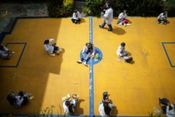 Students wearing COVID-19 protective gear social distance during snack time on their first day back to in-person class since March 2020 at Liceo Lunita, a private school in Chia on the outskirts of Bogota, Colombia, Feb. 5, 2021.