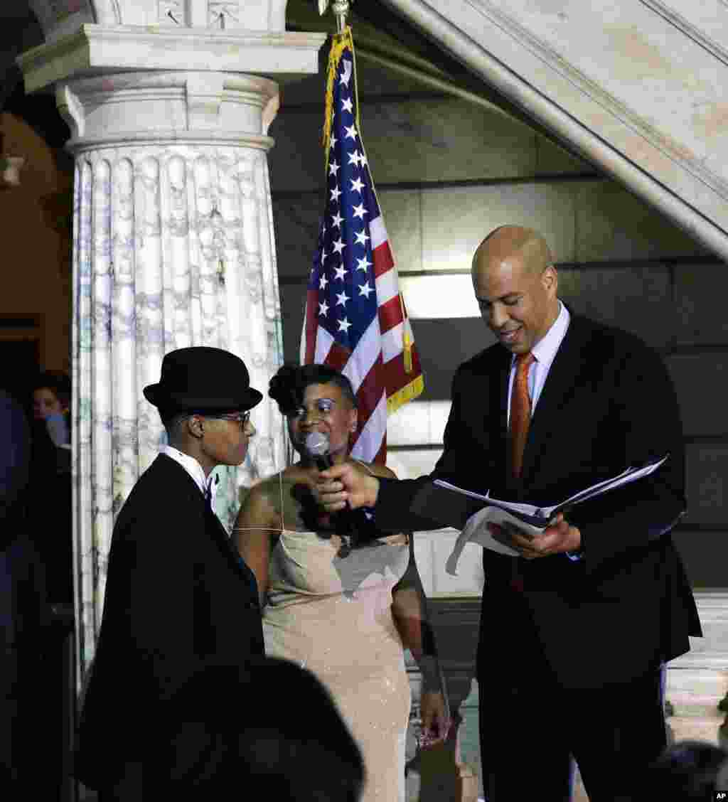 Newark Mayor and Senator-elect Cory Booker, right, officiates the ceremony for the same-sex marriage of Lydia Torres, left, 44, and Jenelle Torres, 42, center, at Newark City hall just after midnight.
