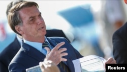 Presiden Brazil Jair Bolsonaro memegang secarik kertas berisi transkrip pesan WhatsApp dengan mantan menteri kehakiman Sergio Moro, di Istana Alvorada, Brasilia, Brazil, 4 Mei 2020.