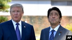U.S. President Donald Trump, left, meets with Prime Minister Shinzo Abe upon the arrival at the Kasumigaseki Country Club in Kawagoe, near Tokyo, Nov. 5, 2017. 