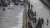 Ljudi prelaze poplavljenu ulicu nakon obilnih padavina u Karačiju, Pakistan, 23. septembar 2021. (Foto: Asif HASSAN / AFP)