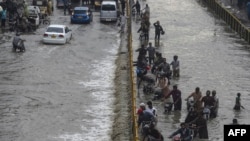 Ljudi prelaze poplavljenu ulicu nakon obilnih padavina u Karačiju, Pakistan, 23. septembar 2021. (Foto: Asif HASSAN / AFP)