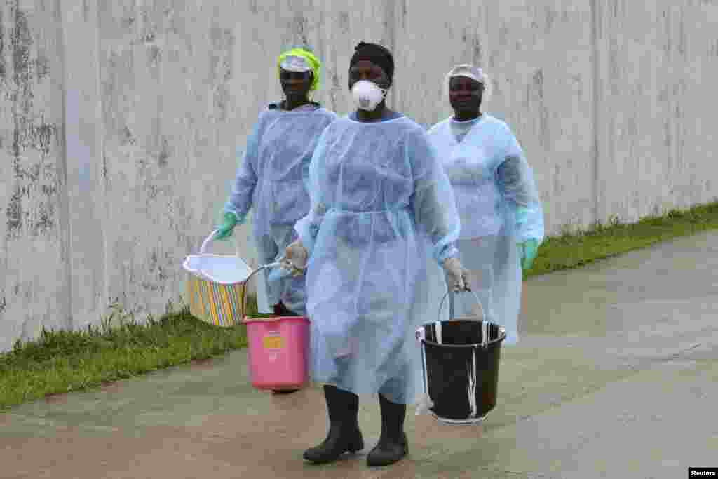 Health workers carry buckets of disinfectant at the newly-constructed Island Clinic and Ebola treatment center in Monrovia, Liberia, Sept. 25, 2014.