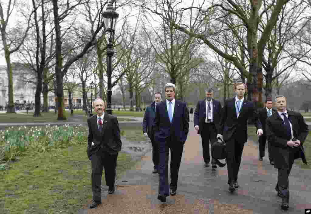 Backdropped by Buckingham Place, U.S. Secretary of State John Kerry, surrounded by aides and security detail takes a walk at the Green Park in central London.