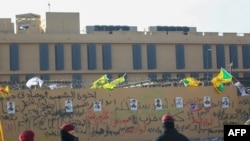 FILE - Portraits of fighters from Kataeb Hezbollah are seen on the wall of the U.S. embassy in the Iraqi capital Baghdad, Jan. 1, 2020, after they were placed by protesters. The militia brushed off U.S. sanctions on the group ver attacks against U.S. forces in Iraq and Syria.