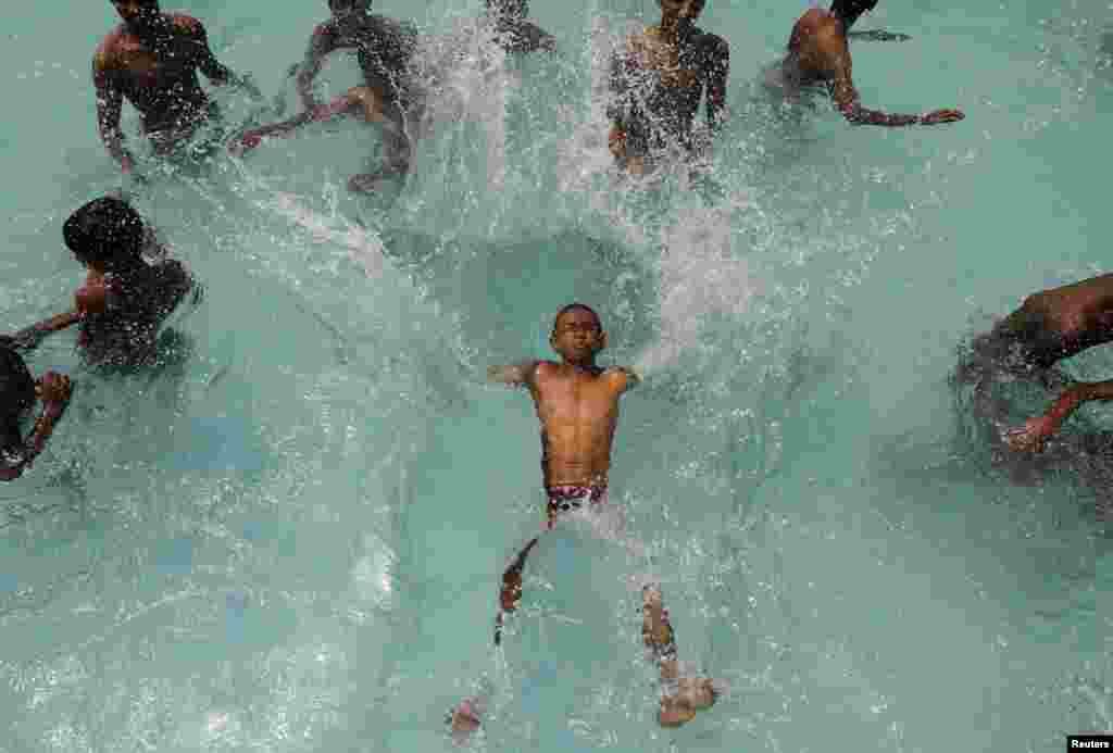 Seorang anak laki-laki melompat ke kolam renang untuk mendinginkan diri pada hari yang panas di kota Chennai, India selatan.