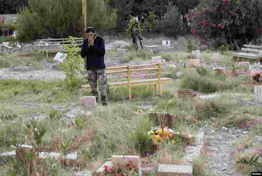 A Free Syrian Army member prays next to the grave of a fellow fighter in a cemetery in Deir el-Zor, May 16, 2013.