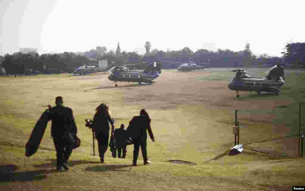 Members of the White House traveling staff walk to a group of helicopters about to transport U.S. President Barack Obama from a soccer field in Johannesburg, June 29, 2013.