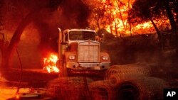 FILE - Flames from the Glass Fire burn a truck in a Calistoga, Calif., vineyard, Oct. 1, 2020. 