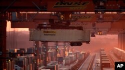 FILE - Shipping containers are offloaded at a BNSF Railway intermodal facility in Edgerton, Kanas, as the sun sets Dec. 20, 2019.