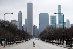 An elderly lady walks across the usually busy Columbus Drive that splits Chicago's Grant Park in half, on the first work day since Illinois Gov. J.B. Pritzker gave a shelter in place order last week, March 23, 2020.