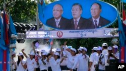 រូបឯកសារ៖ ក្រុម​អ្នកគាំទ្រ​គណបក្ស​ប្រជាជន​របស់​លោក ហ៊ុន សែន រាំ​នៅ​ក្រោម​រូប​របស់​មេដឹកនាំ​គណបក្ស​នេះ ដែល​ពីឆ្វេង​ទៅ​ស្តាំ​គឺ លោក ជា ស៊ីម ដែល​បាន​ស្លាប់​ទៅ​ហើយ លោក ហ៊ុន សែន និង​លោក ហេង សំរិន ក្នុង​ពេល​ឃោសនា​បោះឆ្នោត​មួយ​នៅ​រាជធានី​ភ្នំពេញ នៅ​ខែមិថុនា ឆ្នាំ២០១៣។ 