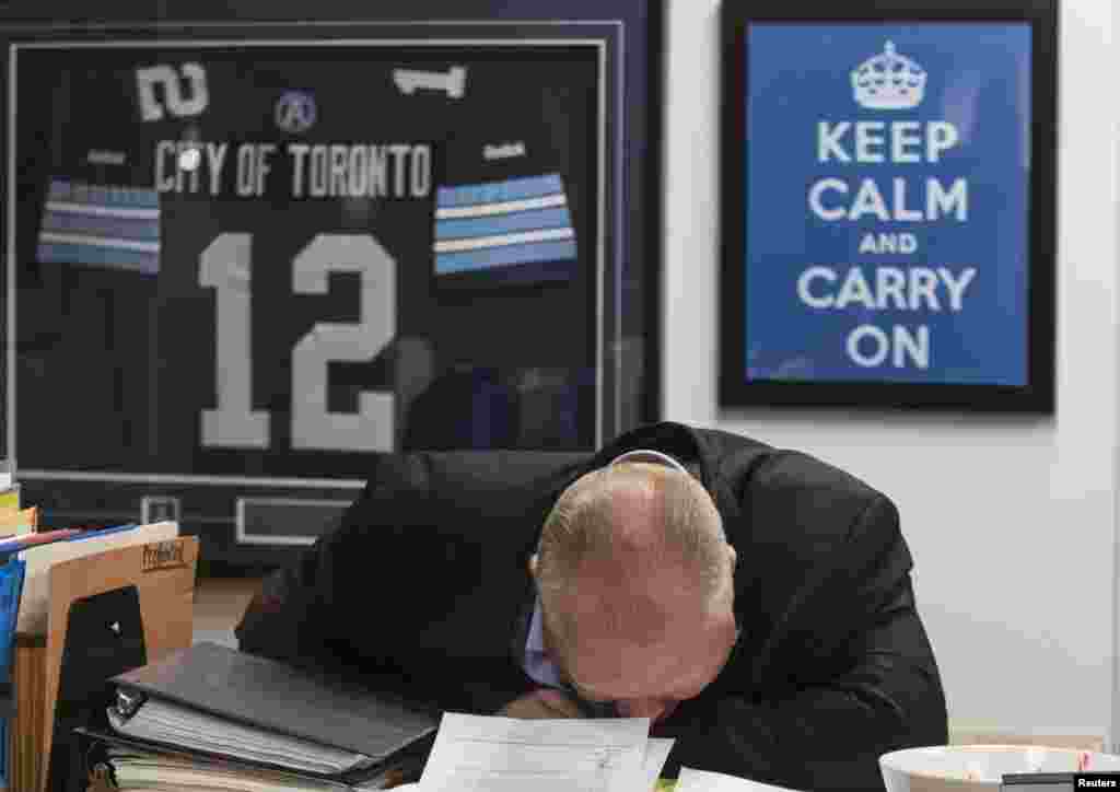 Toronto Mayor Rob Ford laughs in front of a "Keep Calm and Carry On" sign at City Hall in Toronto, Canada, Mar. 19, 2014. Ford, who made global headlines last year after admitting he had smoked crack cocaine, was caught up in fresh controversy after a new video showed him agitated and apparently swearing outside city hall.