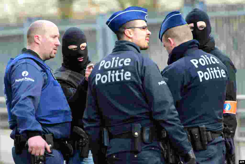 Policemen speak at a security perimeter near Maalbeek metro station, on March 22, 2016 in Brussels, after a blast at this station near the EU institutions caused deaths and injuries.