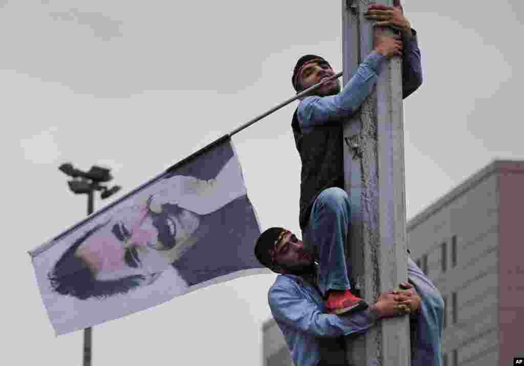 A supporter of the pro-Kurdish Peoples' Democratic Party (HDP) is helped to climb a pole with a flag of imprisoned Kurdish rebel leader Abdullah Ocalan, during a rally in Istanbul, Turkey, June 8, 2015, a day after the elections.