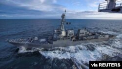 El destructor USS Kidd navega junto al portaaviones USS Theodore Roosevelt durante maniobras militares en el golfo de Alaska, el 16 de mayo de 2019. En estos momentos, ambas naves permanecen en puerto debido al nuevo coronavirus.