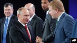 លោក Putin (ឆ្វេង) ចាប់​ដៃ​ជាមួយ​លោក Myron Brilliant អនុប្រធាន​ប្រតិបត្តិ​ និង​ជា​ប្រធាន​កិច្ចការ​អន្តរជាតិ​នៅ​សភាពាណិជ្ជកម្ម​អាមេរិក នៅ​ក្នុង​ទីក្រុង St. Petersburg ប្រទេស​រុស្ស៊ី កាល​ពី​ថ្ងៃទី​២ ខែមិថុនា។