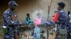 A young girl's face is engulfed in smoke as Malian soldiers patrolling with Tuareg Malian soldiers under the command of Colonel El-Hadj Ag Gamou stop for a cigarette break in the streets of Gao, northern Mali, Feb. 16, 2013. 