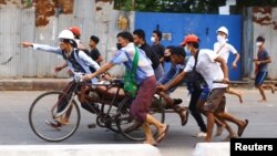 បាតុករ​មីយ៉ាន់ម៉ា​នាំ​គ្នា​រុញ​ជនរងគ្រោះ​ម្នាក់​​ដែល​ត្រូវ​បាន​ប៉ូលិស​បាញ់​ទៅ​រក​កន្លែង​សុវត្ថិភាព ក្នុង​អំឡុងពេល​​កងកម្លាំង​សន្ដិសុខ​បង្ក្រាប​បាតុកម្ម​ប្រឆាំង​នឹង​រដ្ឋប្រហារ​នៅ​ទីក្រុង​រ៉ង់ហ្គូន ថ្ងៃទី១៤ ខែមីនា ឆ្នាំ២០២១។ 