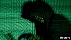 FILE PHOTO: Man holds laptop computer as cyber code is projected on him in this illustration picture