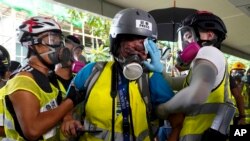 Indonesian journalist Veby Mega, center, injured in the eye by what was believed to be a police-fired projectile, is being attended by others, during potests in Hong Kong, Sept. 29, 2019.